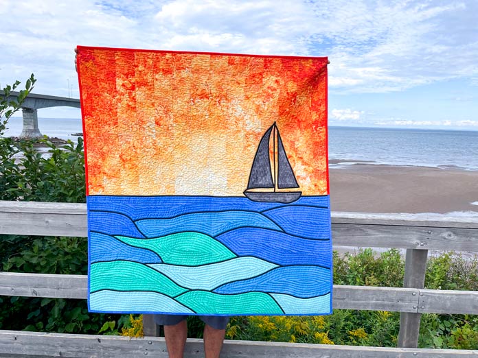 A quilt of a sailboat at sea during sunset.