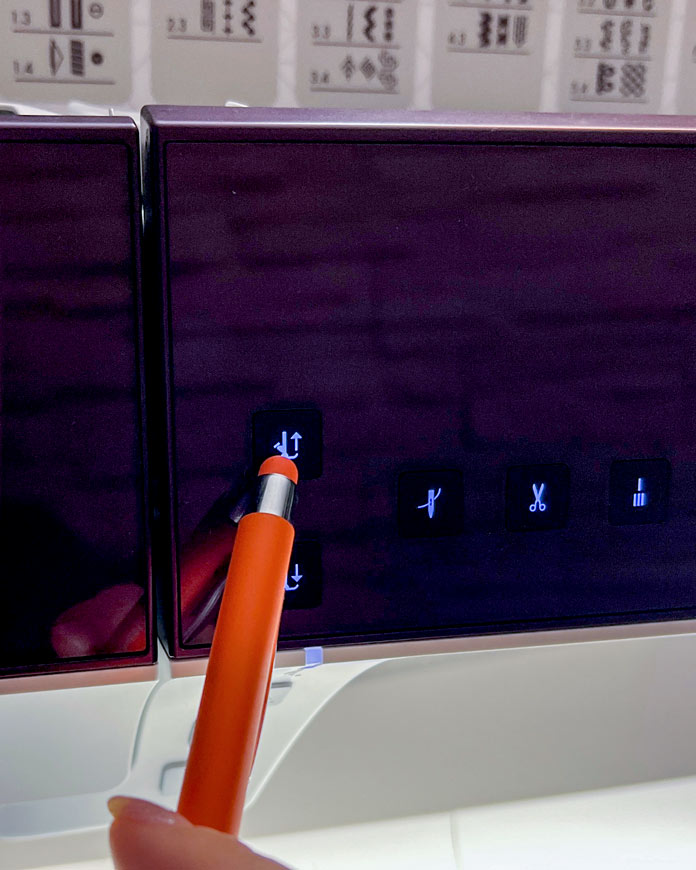 A close-up view of the physical control panel on the PFAFF creative icon 2 sewing machine. A stylus is shown pressing the half-lift presser foot button, which raises the presser foot slightly while keeping the needle down: ideal for accurate ribbon placement with trims like velvet or braid.