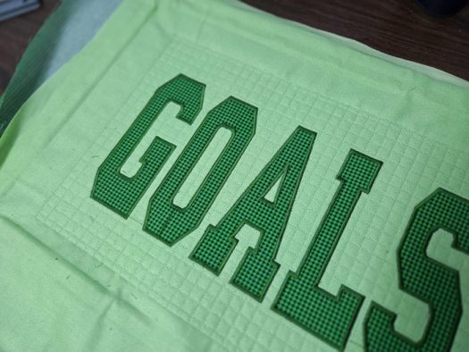 The word GOALS in green fabric
