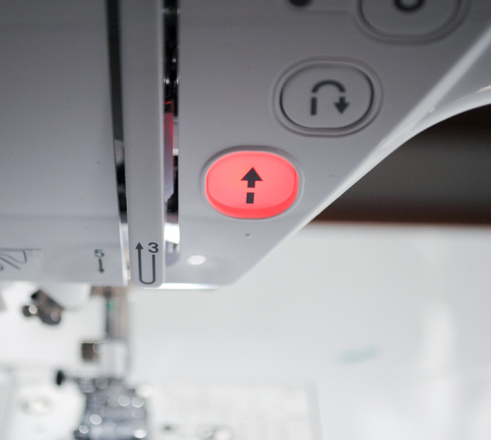 A close up photo of the red stop/start button on the NQ900 sewing machine. Brother NQ900 sewing machine