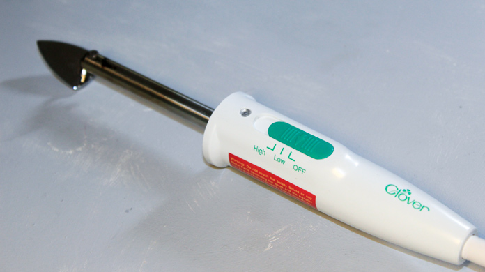 The original Clover mini iron with a metal tip and white and green handle has a switch with 3 heat settings 