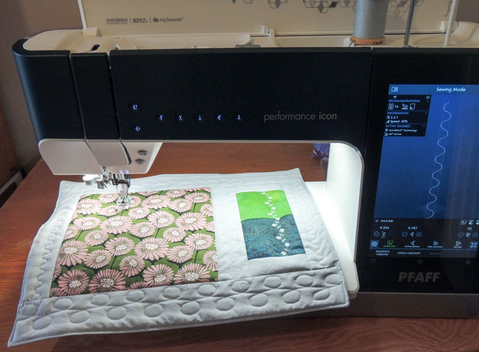 A quilted placemat on the bed of a computerized sewing machine. PFAFF performance icon, Stitch-in-Ditch Foot, Embroidery/Sensormatic Free-Motion Foot