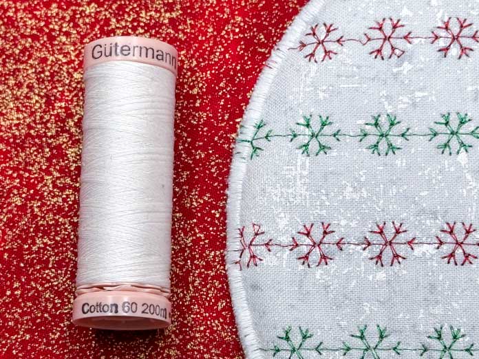 The portion of the decoration’s edge with a spool of Gütermann cotton 60wt white thread. 