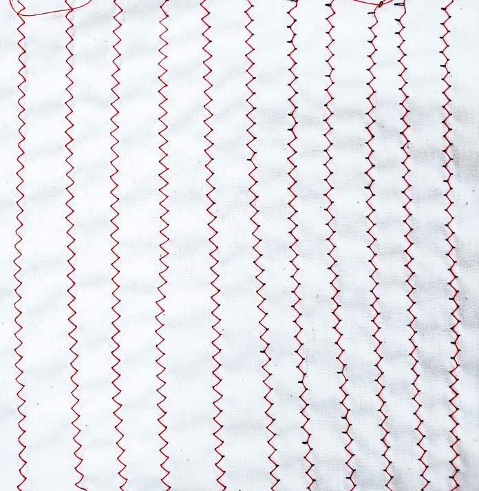 Ten lines of zigzag stitching in red thread using various tension settings. Husqvarna Viking Designer Ruby 90