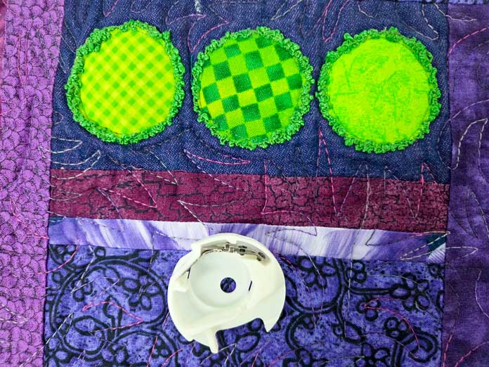 Green fabric circles on a purple quilt
