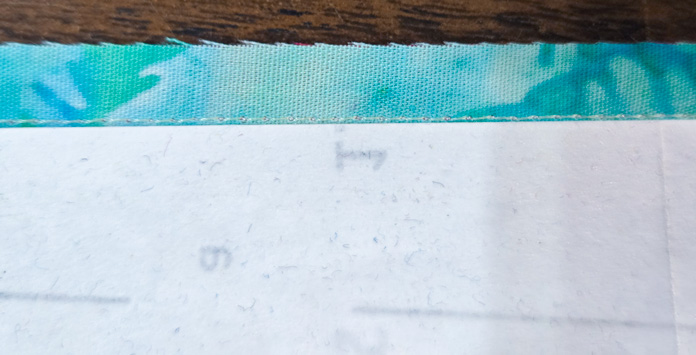A line of white stitches beside a piece of folded paper