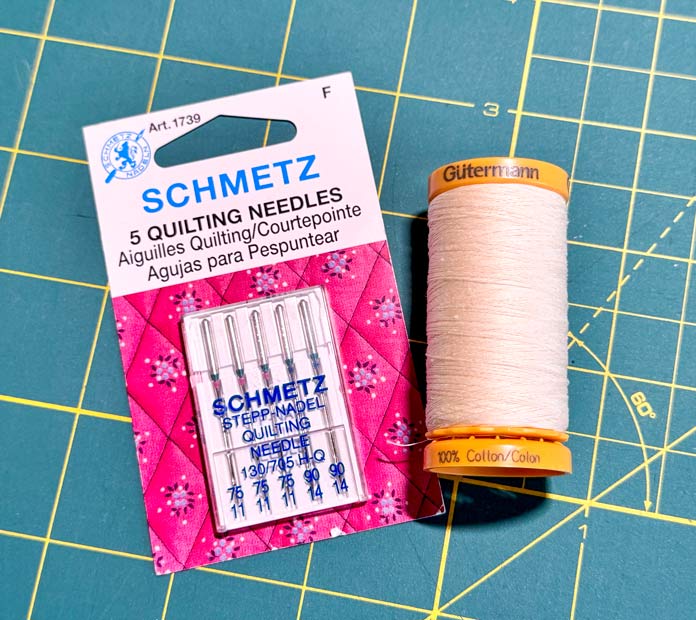 A card of SCHMETZ quilting needles and a spool of Gütermann cotton thread. 