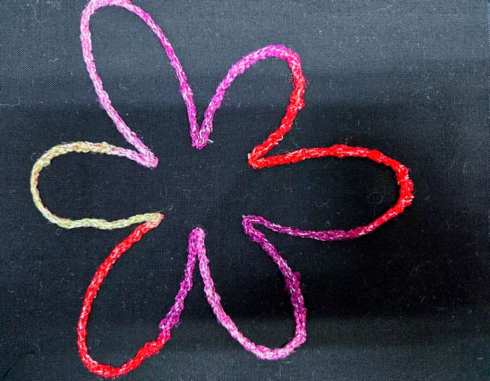 A flower shape in red and purple yarn on black fabric