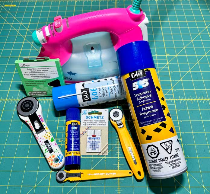 Tools and notions used to create this week’s landscape quilt, OLFA rotary cutters, 45mm, 28mm and 18mm, SCHMETZ twin needle, Odif 606 fusible Adhesive web, Oliso PRO TG1600 Pro Plus Smart Iron, Odif 505 Temporary Adhesive Glue Stick, Clover Quick ¼” black Bias Tape