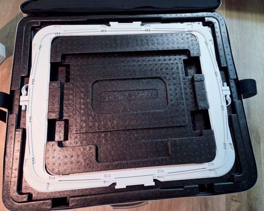 A large plastic grey machine embroidery hoop in a black case