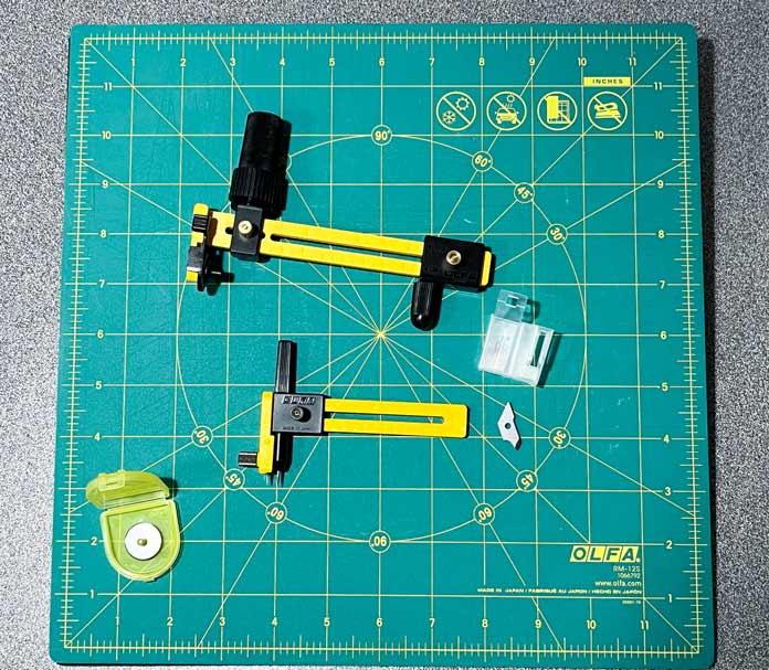 OLFA Rotary Circle Cutter, OLFA Compass Circle Cutter with additional blades, and OLFA 18mm Rotary Blades on an OLFA Square Rotating Cutting Mat