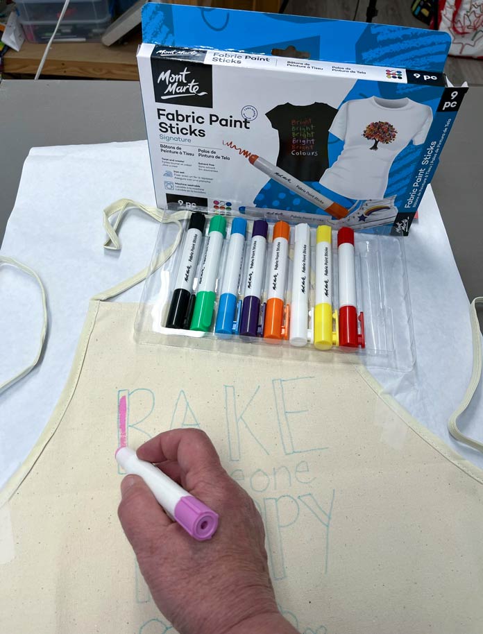 Coloring in the design on an apron using paint sticks; Mont Marte Fabric Paint Sticks, Fabric Fun Apron for Embellishment