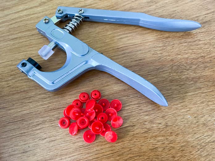 UNIQUE Sewing Snap Fastener Tool and red plastic snaps sitting on a table