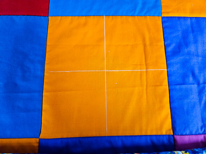 An orange square on a quilt with white chalk lines; Clover Chaco Liner