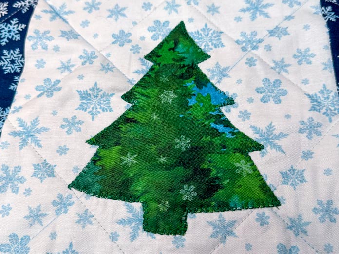 A tree is appliqued using a blanket stitch.