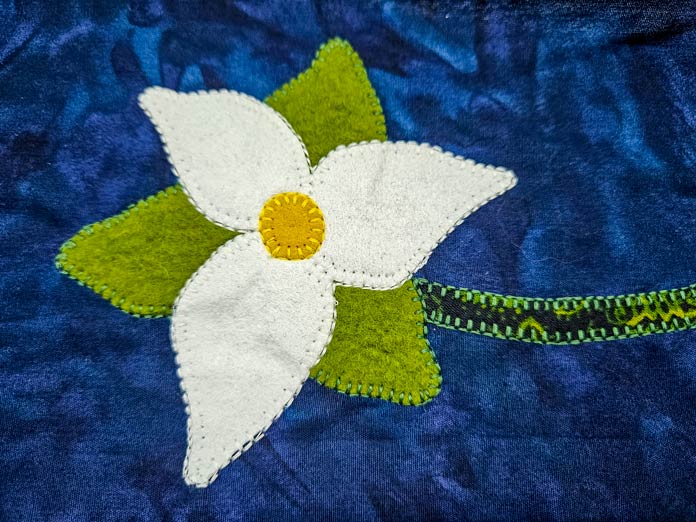 A white and green flower on a blue fabric; Husqvarna VIKING DESIGNER EPIC 3