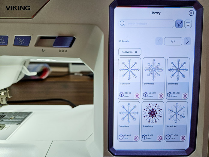 A screen on a computerized sewing and embroidery machine shows 6 different snowflake embroidery designs; Husqvarna VIKING Designer Quartz 29, mySewnet Machine Embroidery Software, mySewnet Library, Husqvarna VIKING Tear-a-Way Light Stabilizer 15 Inches x 25 Yards