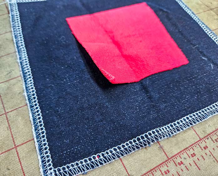 A red square on blue denim; HeatnBond, fusible web, sewing, applique, quilting, hemming, fabric adhesive, SoftStretch, Lite, Featherlite, Ultra, sewing tips, crafting, fabric experiments