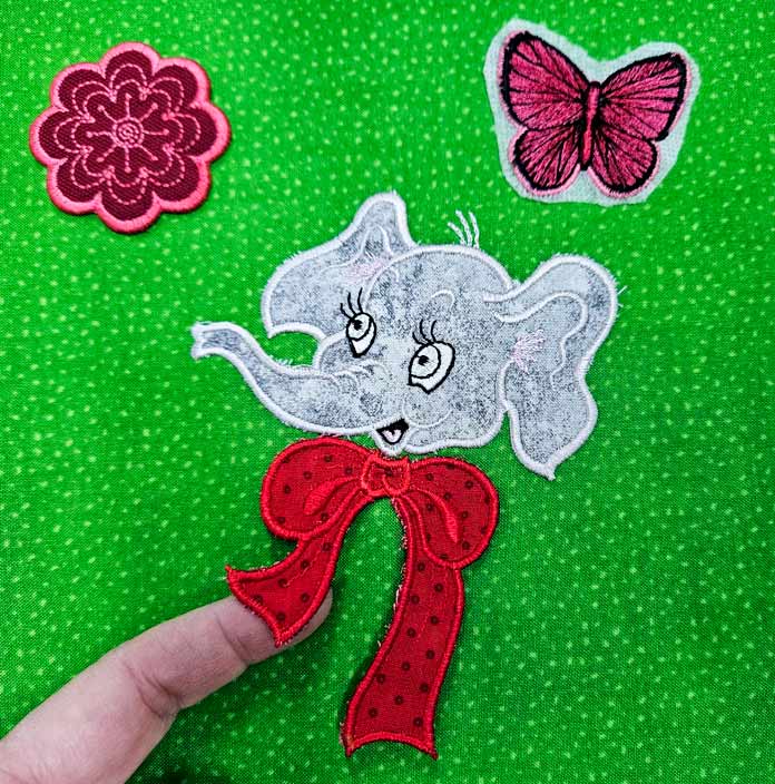 A pink flower, a pink butterfly, and a grey elephant on green fabric; machine embroidery, quilting, applique, cutwork embroidery, free-standing lace, embroidery techniques, HUSQVARNA VIKING, Designer Epic 3, mySewnet, JoyOS Advisor