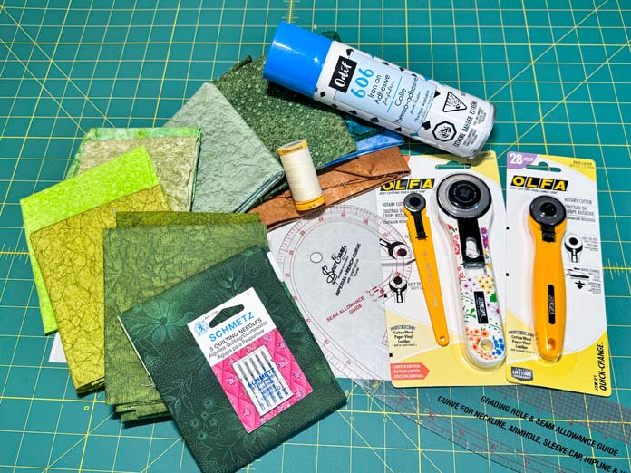 fabrics, three OLFA rotary cutters and 18mm, 45mm and a 28; A spool of Gütermann thread, a Pack of SCHMETZ quilting needles and a can of Odif 606 iron-on adhesive spray. 