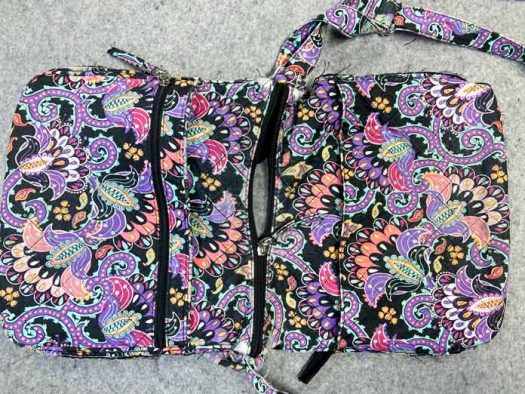 A multicolored purse that has had its side seams removed lays on a grey pressing mat. 