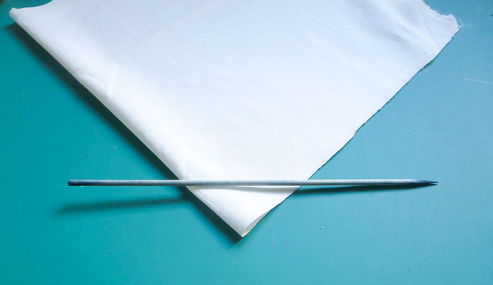 A wooden skewer in placed on one corner of white fabric
