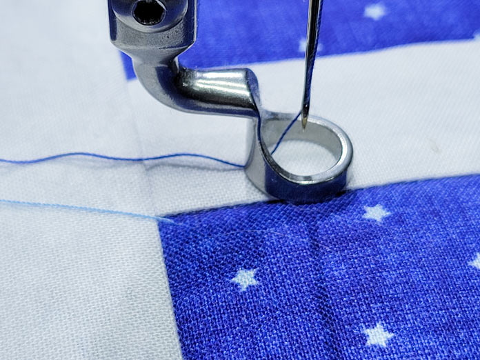 Blue thread on blue and white fabric with the presser foot of a quilting machine; PFAFF powerquilter 1600