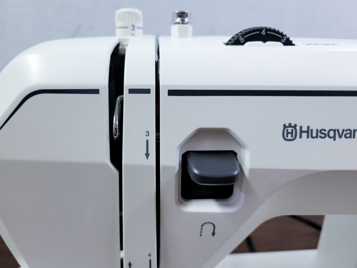 A black lever on the front of a white sewing machine; on the Husqvarna VIKING ONYX 25