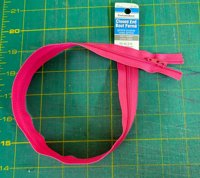A pink zipper on a green cutting mat; using the Husqvarna VIKING ONXY 25 to sew it up