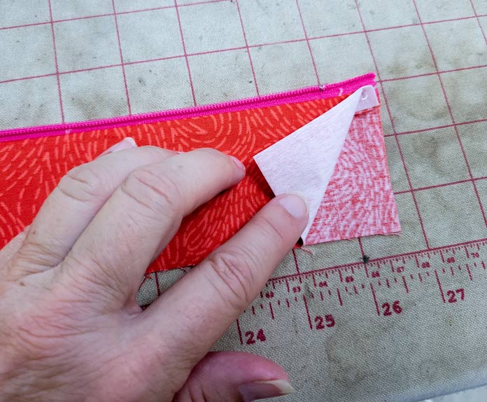 A hand on orange fabric with a pink zipper; making a project bag on the Husqvarna VIKING ONYX 25