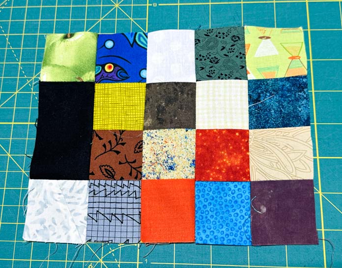 A black rectangle to a block with a 2” x 2” square at each end is sewn to a 16-patch block.