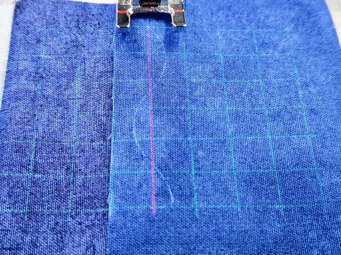 A projection of a green grid, a red straight line, and a blue wavy line on blue fabric. Husqvarna VIKING DESIGNER EPIC 3 sewing and embroidery machine, Husqvarna VIKING 6in/15.2cm Applique Scissor, Husqvarna VIKING Open Toe Presser Foot for IDF System, SULKY Slimline Metallic Dream Assortment