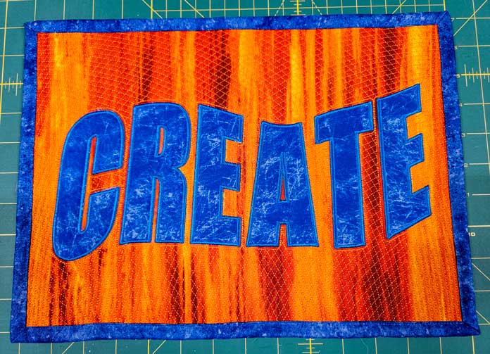 Blue letters on orange fabric; machine embroidery, quilting, mySewnet, HUSQVARNA VIKING, embroidery software, digital embroidery, quilt block wizard, applique, embroidery design, monogramming