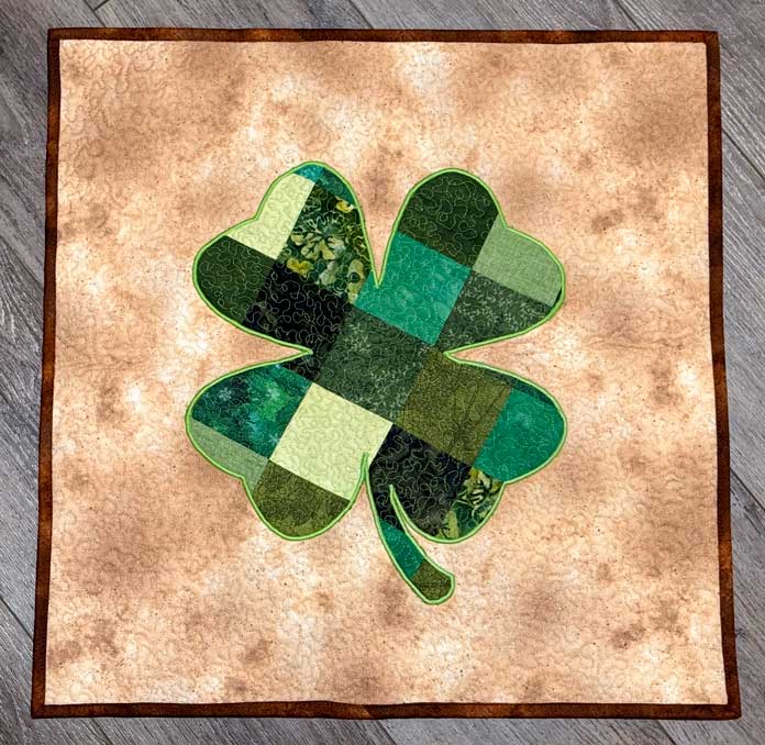 The completed green four-leaf clover on a cream-colored background quilt.