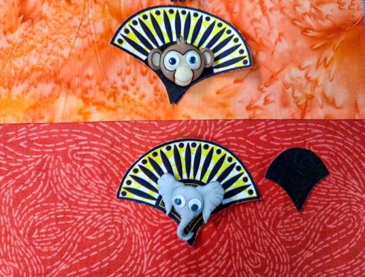 A monkey and elephant button on orange fabric
