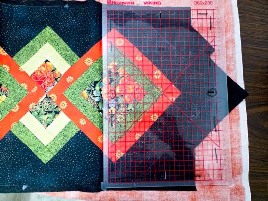 A black and green table runner with a plastic template with red grid lines
