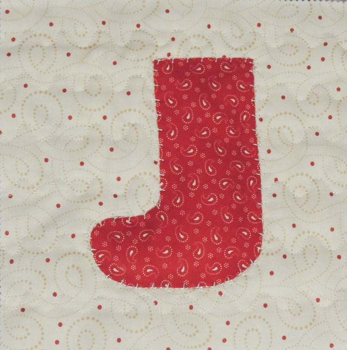 A red stocking appliqued on quilted cream print fabric