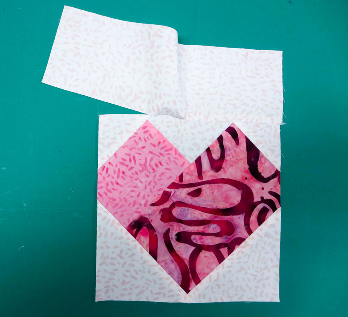 A 3" x 9” strip is sewn to the top of the heart block with a partial seam.