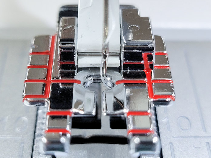 The sewing machine needle is to the right of center position with a metal presser foot; Husqvarna Viking Tribute 150C