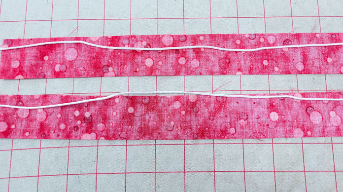 Two strips of red fabric with white cording on top