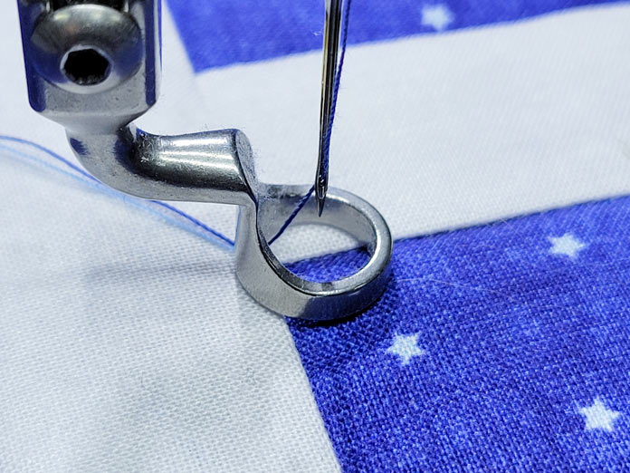 A blue and white fabric under the presser foot of a quilting machine; PFAFF powerquilter 1600