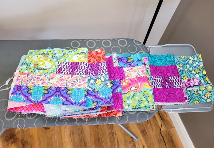 Four rows of multi-colored fabric on a gray ironing board