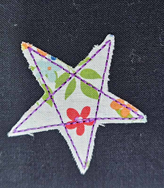 A white fabric star with purple stitching on black fabric; Husqvarna VIKING DESIGNER EPIC 3