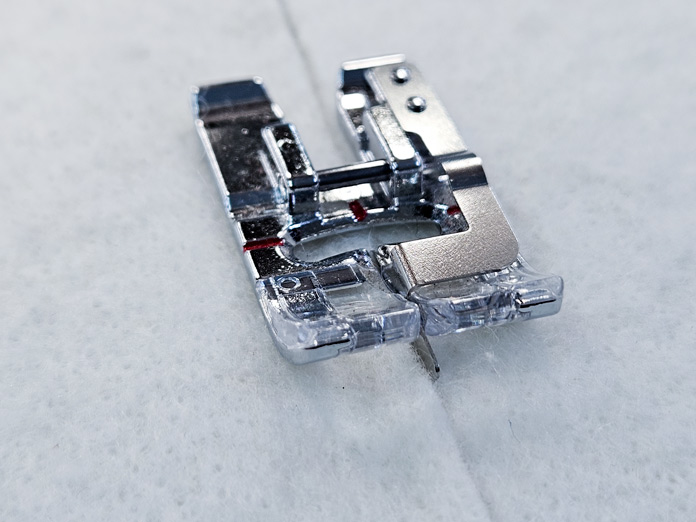 A metal presser foot with a flange in the middle