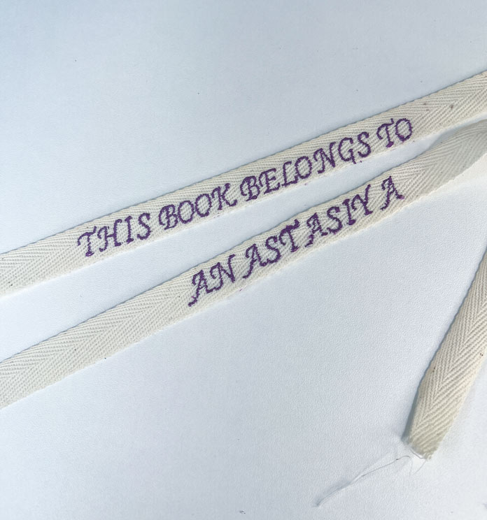 Two finished laces with embroidered sayings, dried and pressed with the right sides up. 