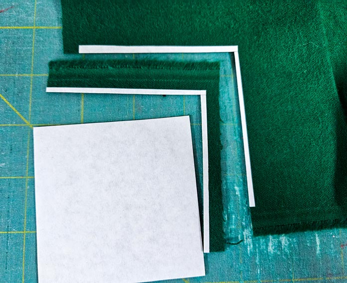 A white square with green fabric; Learn how to use HeatnBond SOFTSTRETCH fusible web on knits, denim, fleece, and more