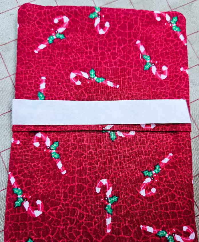 Red fabric with candy canes and a white strip of adhesive tape; HeatnBond Lite, quilt binding, fusible web, fabric crafts