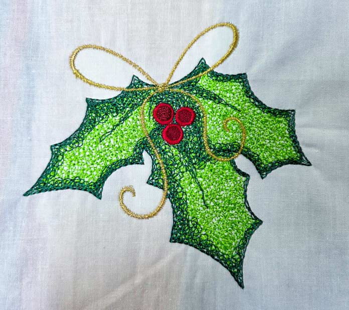 A machine-embroidered holly leaf with a metallic thread bow