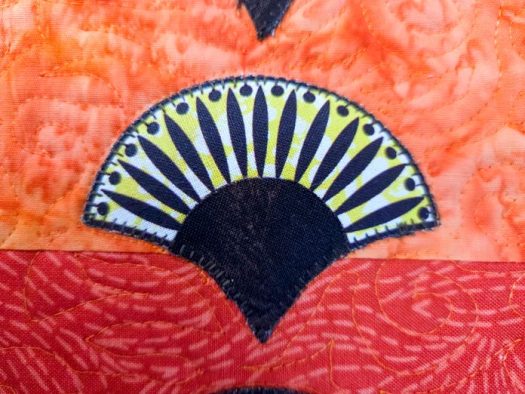A brown and yellow appliqué on orange fabric