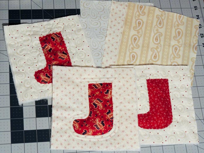 Three cream-colored squares quilted and each with a red stocking appliqued on top
